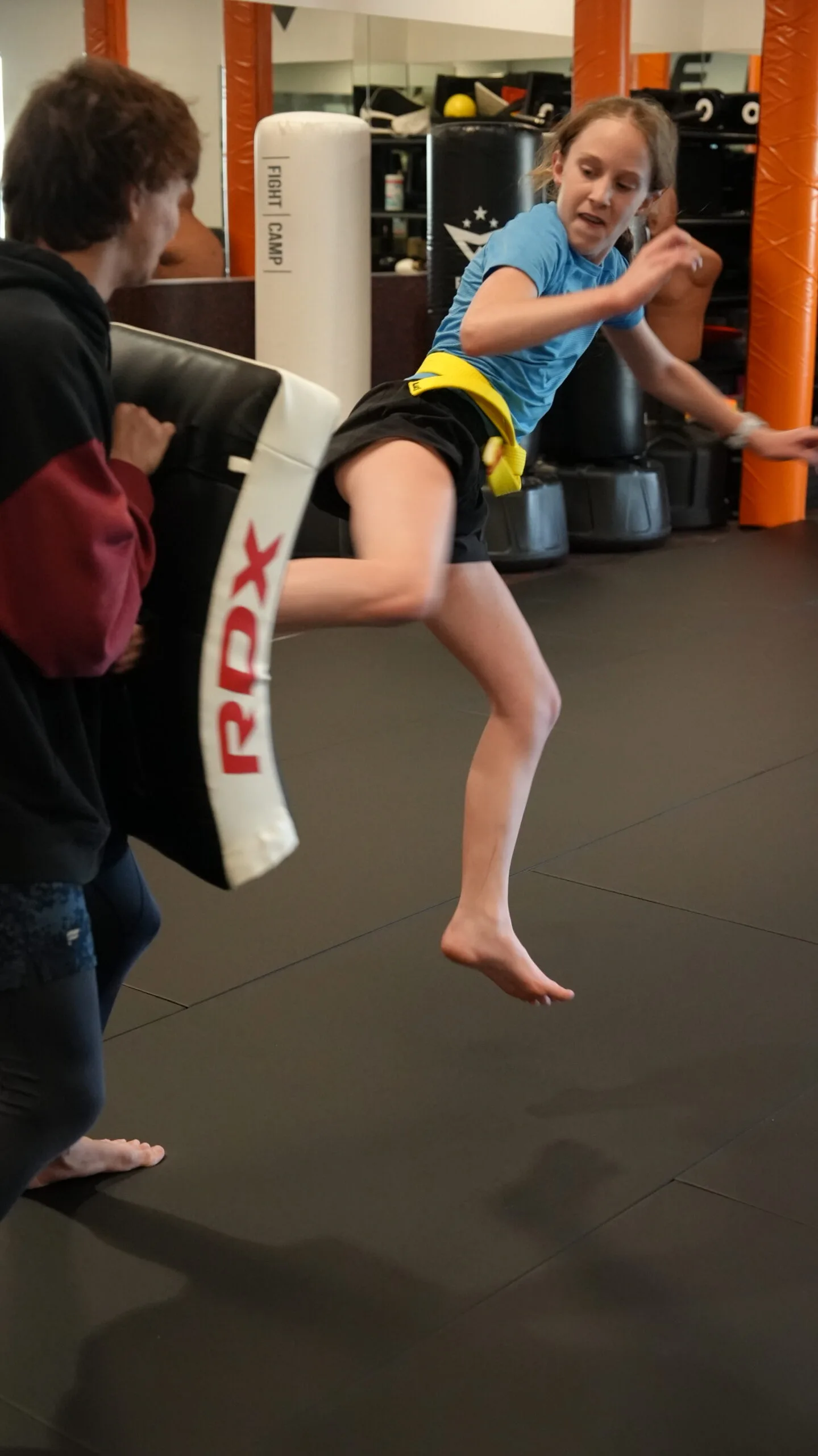 A teen practices a high kick during a Forge Athletics youth training session in Naples