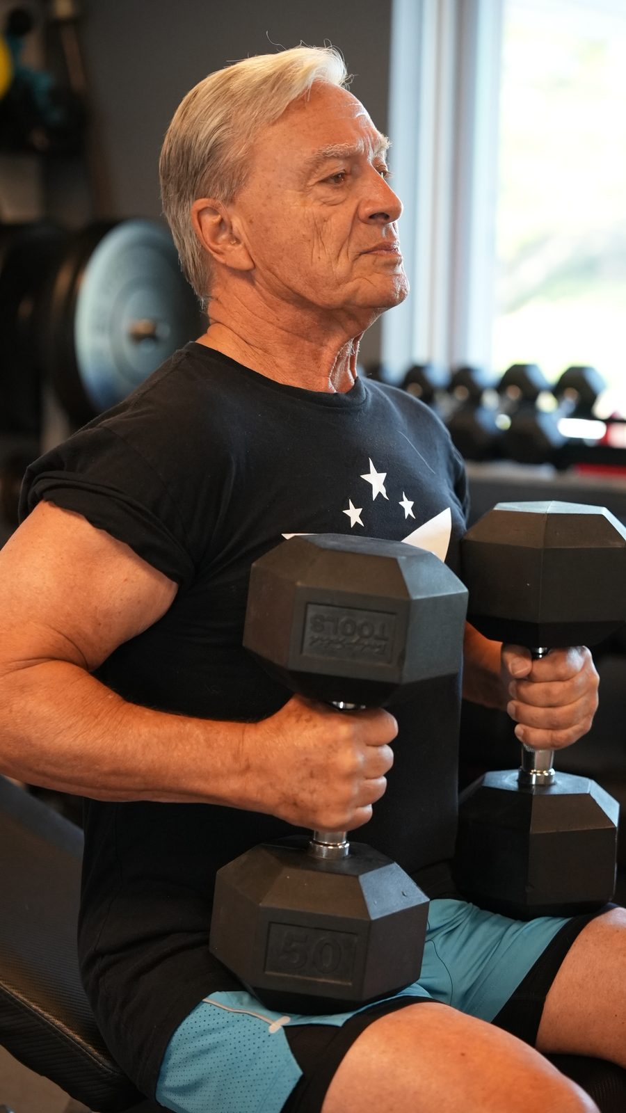 A senior member pressing dumbbells during a coached session