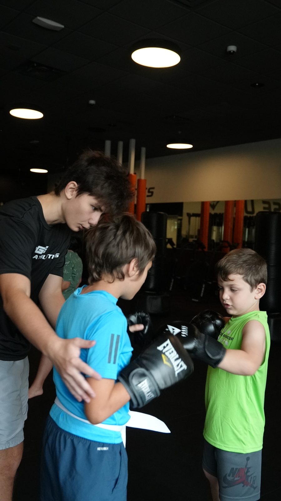 Coach helping two young students with their gloves