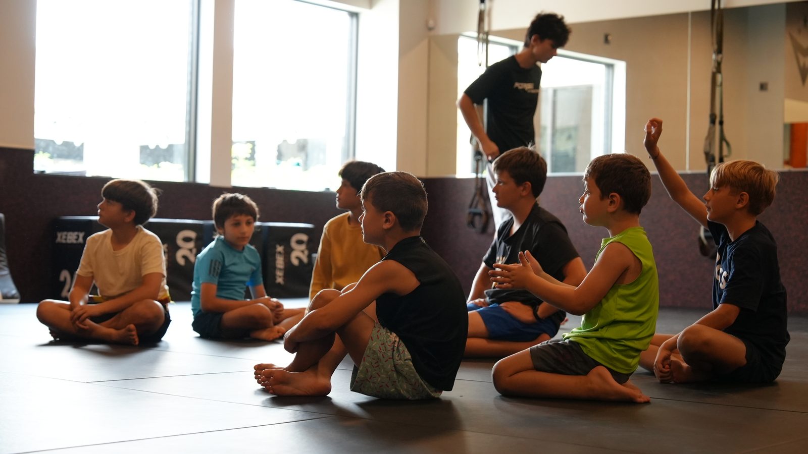 Campers sit in a circle listening to a coach during kids summer camp at Forge Athletics in Naples