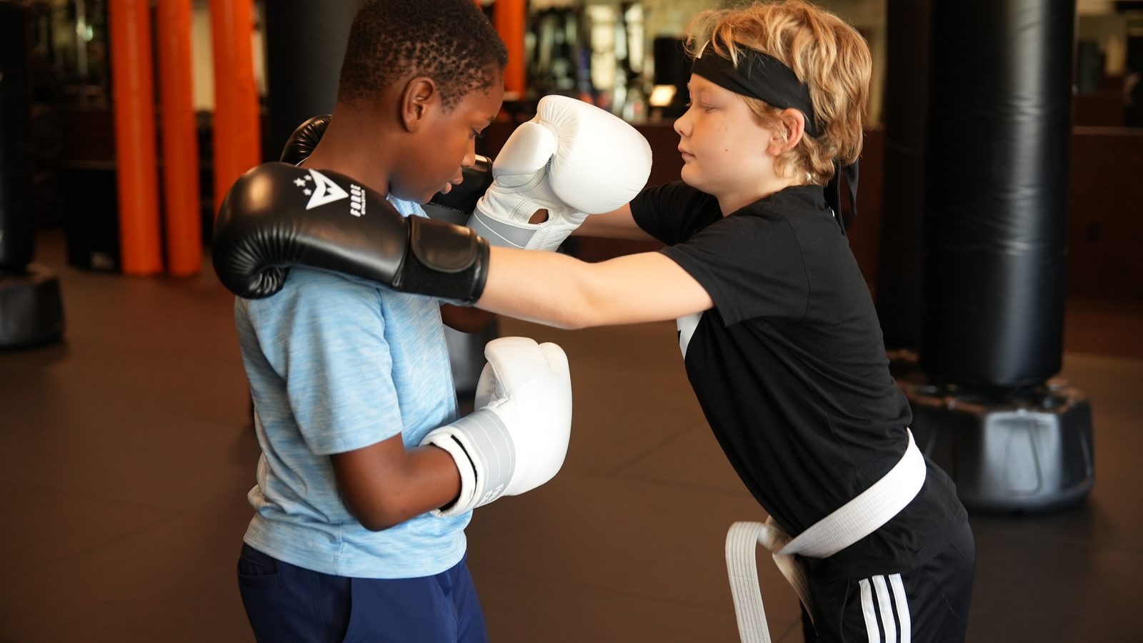 Two young students square up in boxing gloves for a partner drill at Forge Athletics in Naples