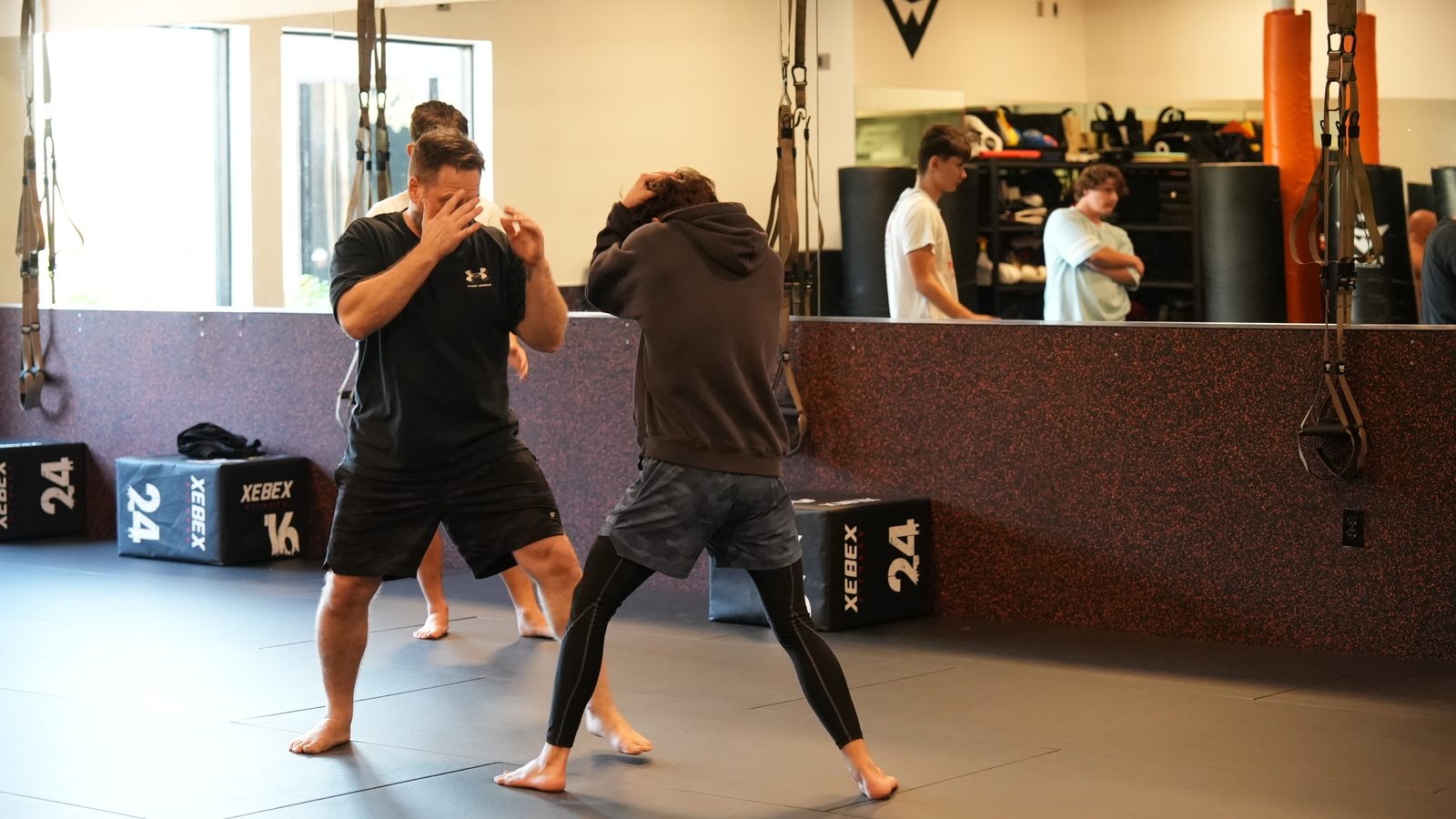 Two adult members work a boxing drill with hands up on the training floor at Forge Athletics in Naples