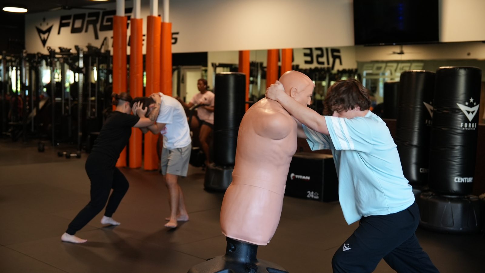 Two members practice strikes on a training dummy during a self-defense class at Forge Athletics in Naples