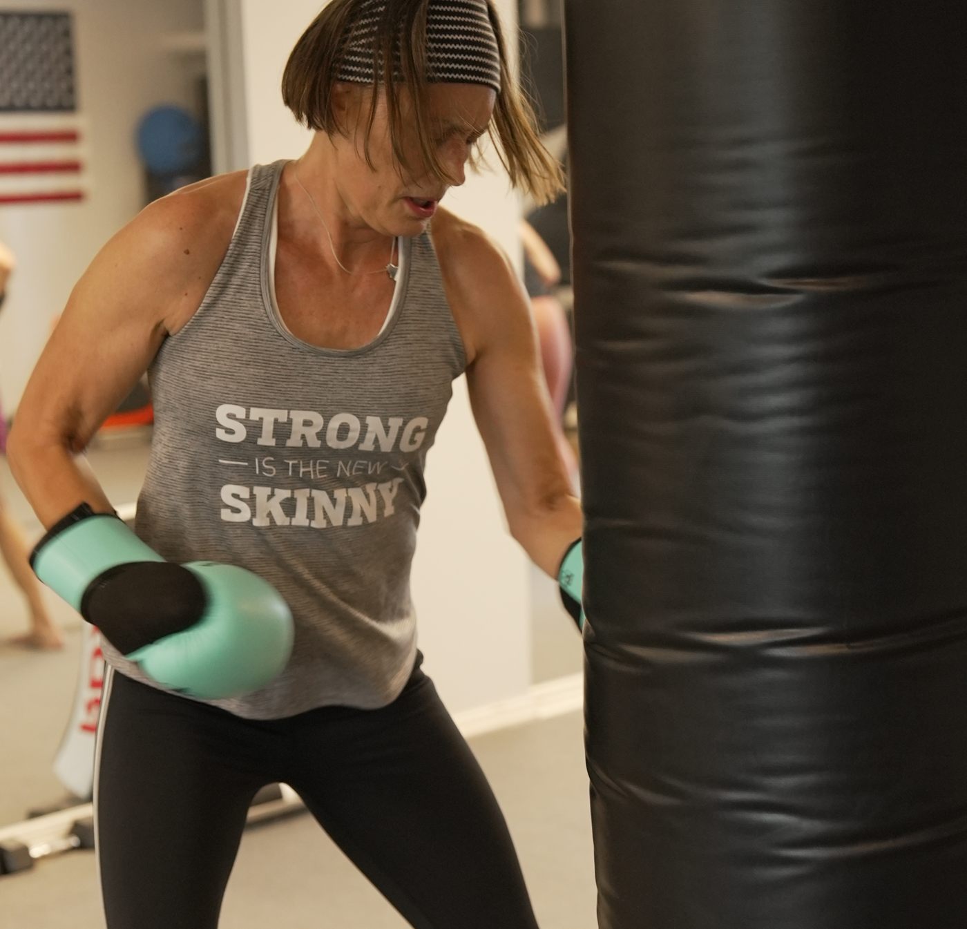 A member drives a punch into the heavy bag during a striking round at Forge Athletics in Naples