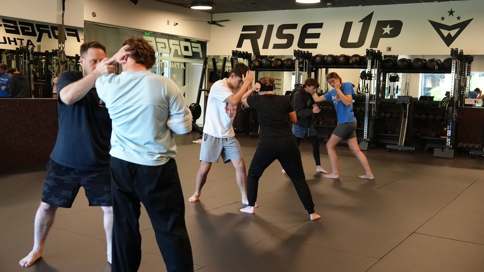 Adult students drill partner self defense under the Rise Up wall at Forge Athletics in Naples