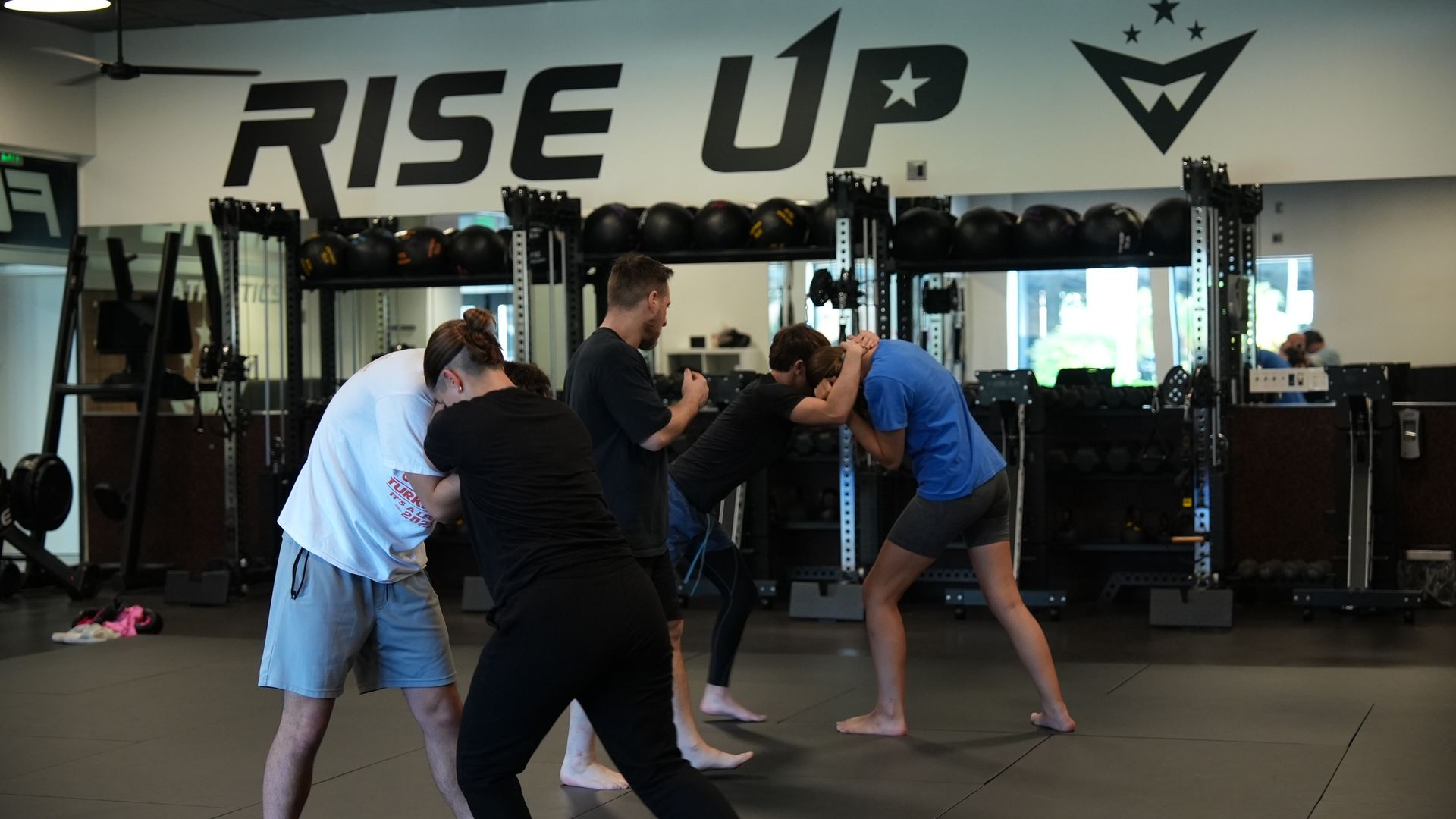 Pairs drill clinch control under a coach's eye during MMA training at Forge Athletics in Naples