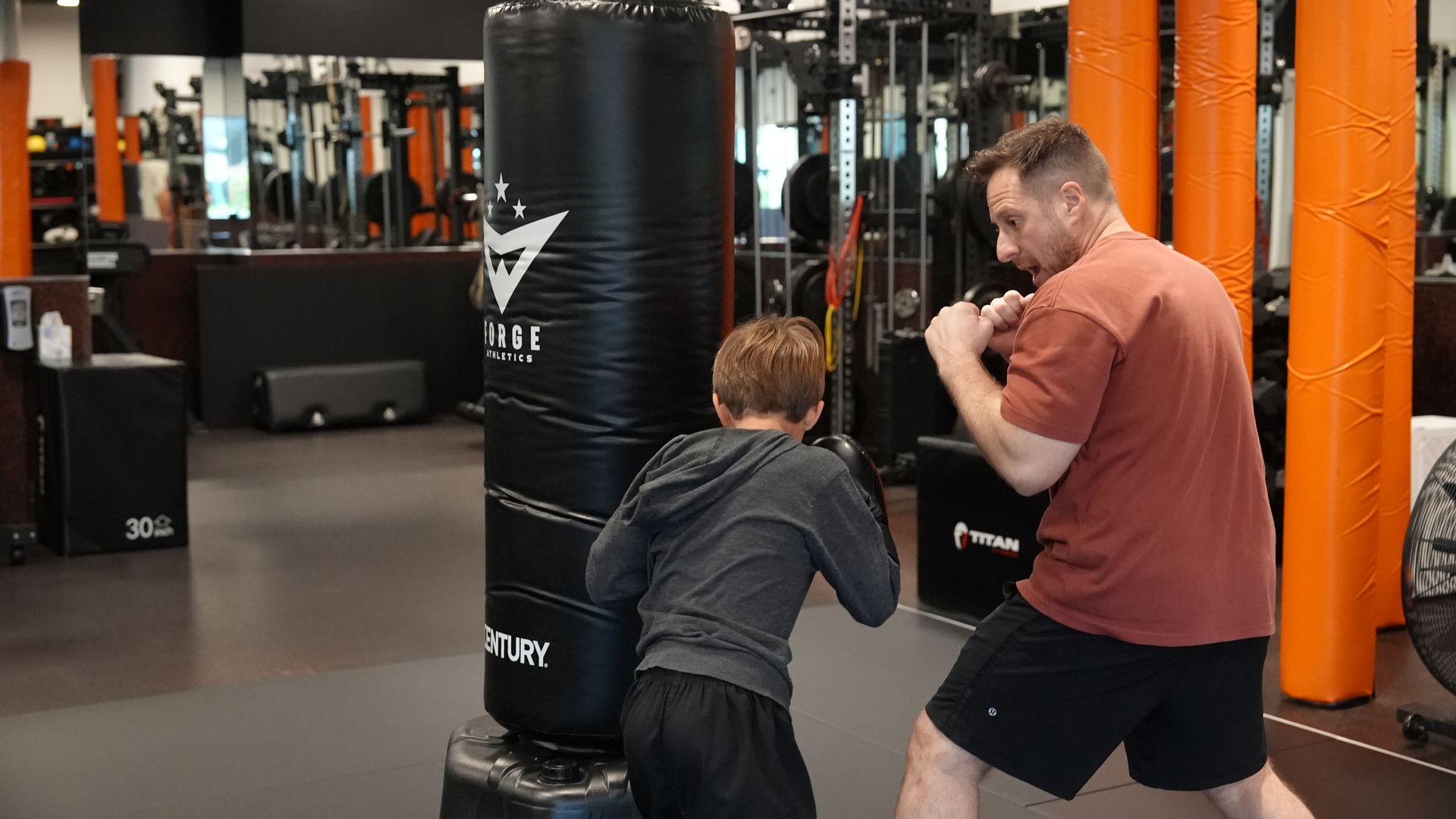 Coach Wil coaches one young student through a boxing round at the Forge Athletics bag in Naples