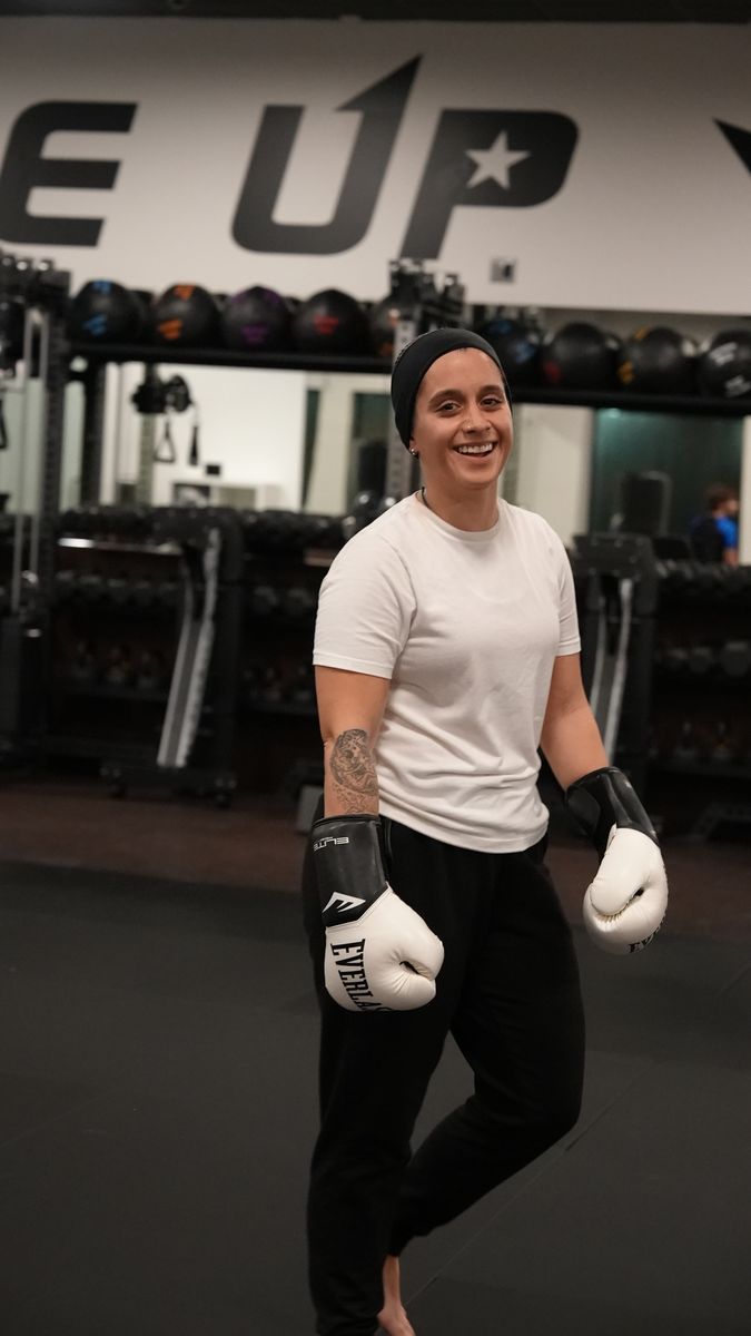 A smiling member in boxing gloves during women's personal training at Forge Athletics in Naples