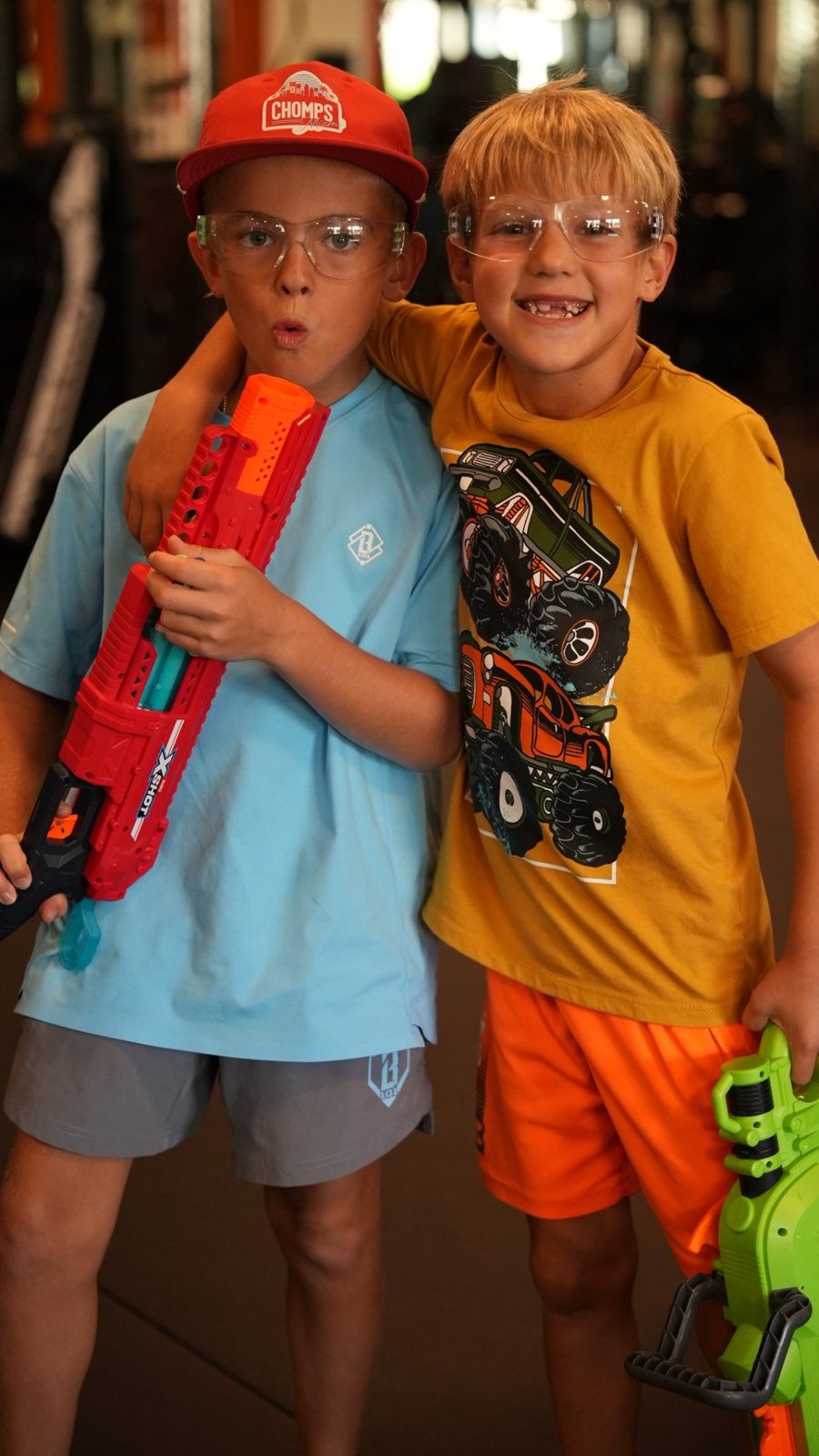 Two boys in safety goggles grin with their Nerf blasters at Forge Athletics in Naples