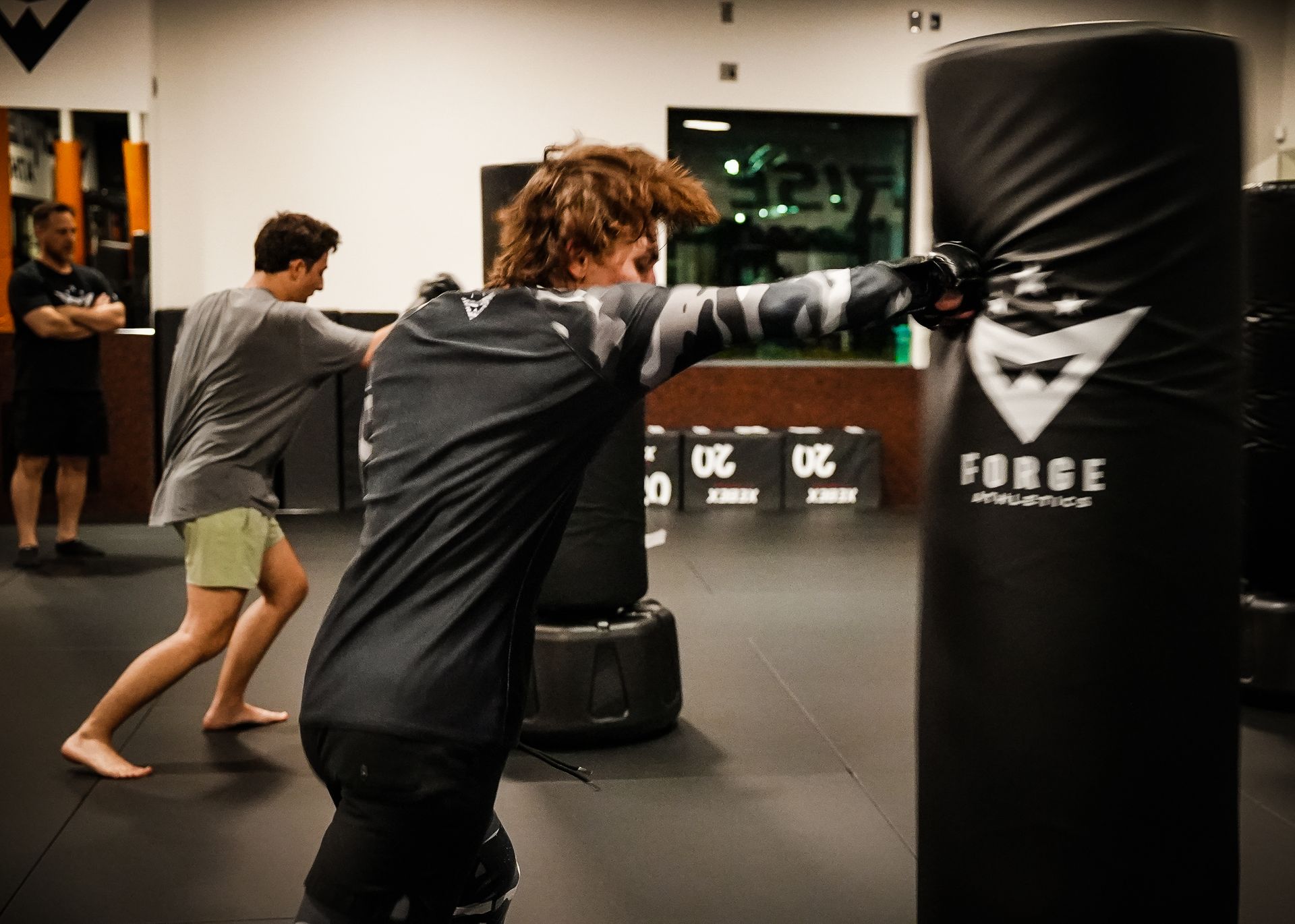 A teen student drives a punch into the heavy bag during MMA-based training at Forge Athletics in Naples