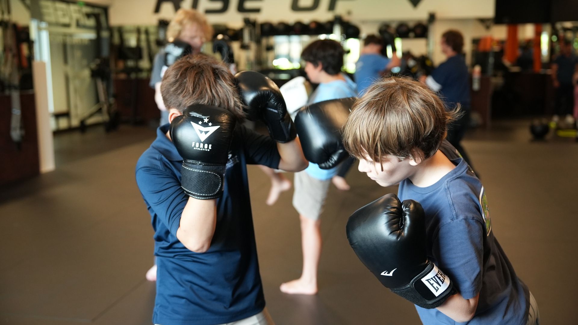 Two youth students square up in boxing gloves during a coached Youth MMA drill at Forge Athletics in Naples