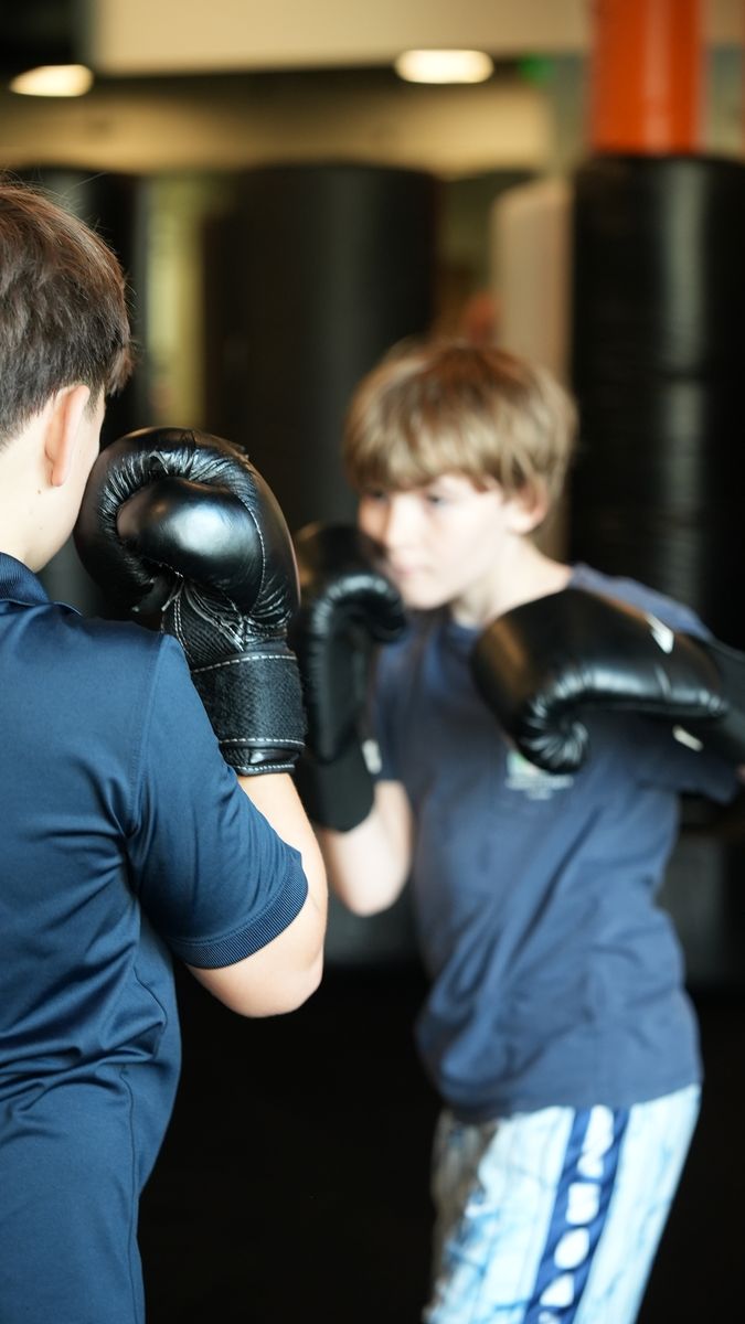 A young student holds his guard up, eyes locked on his partner, during a Youth MMA drill at Forge Athletics