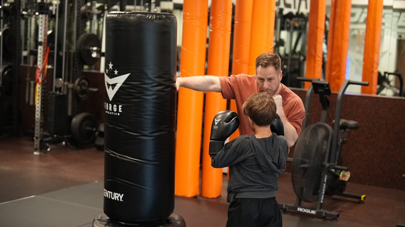 Coach Wil coaches a young student at a Forge Athletics bag in the new Coastland gym