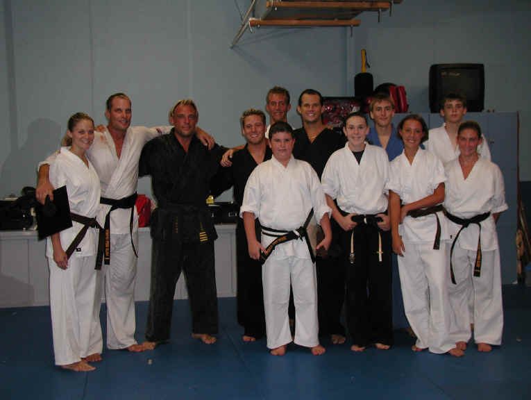 Wil Pino with a group of his students holding their new black belt certificates at Elite Martial Arts