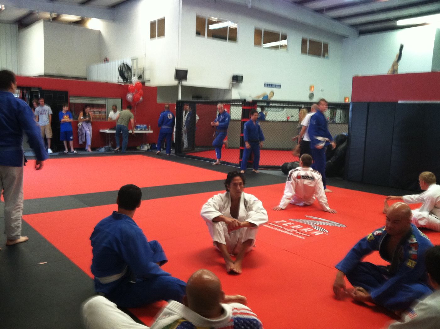 The Elite Martial Arts MMA training area with cage and open mats full of students