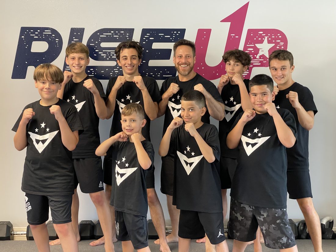 The first group of Forge Athletics students posing under the RISE UP wall at the original Naples studio
