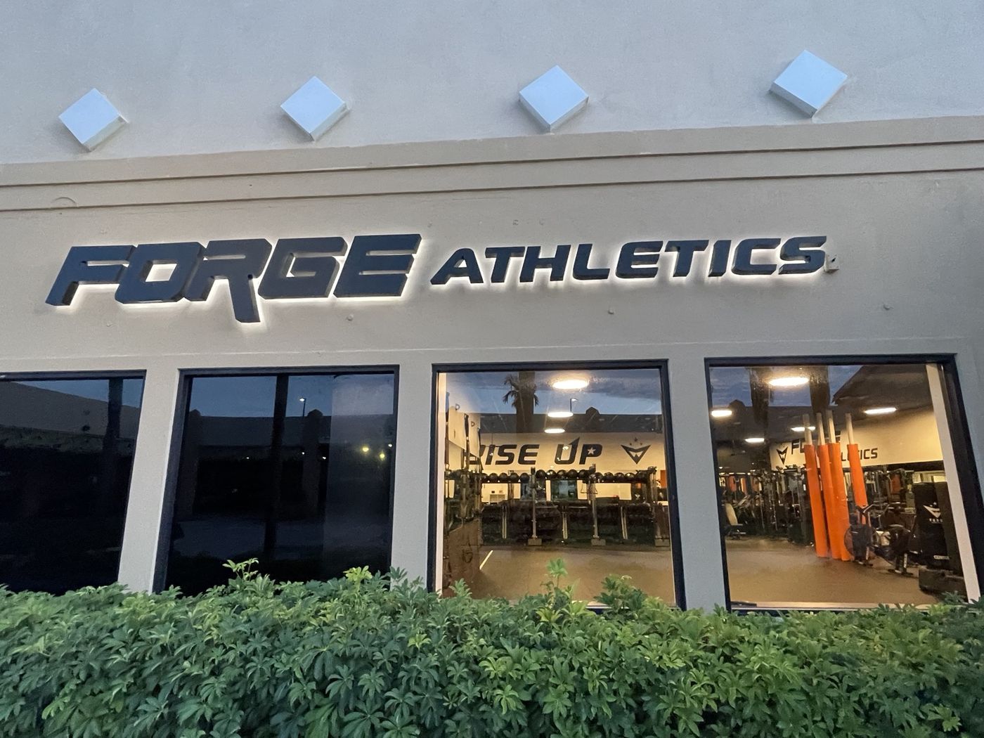 The Forge Athletics sign above the gym windows at Coastland Center, with the RISE UP wall visible inside
